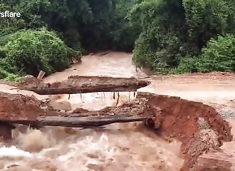 Deux hommes en moto empruntent une route de terre emportée par les eaux