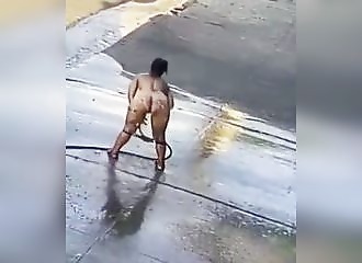 She takes advantage of a garden hose to do her toilet