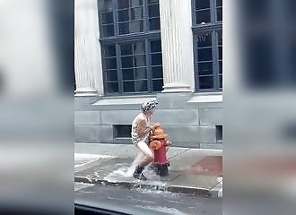 Une vieille femme se fait du bien avec le jet de la bouche d’incendie